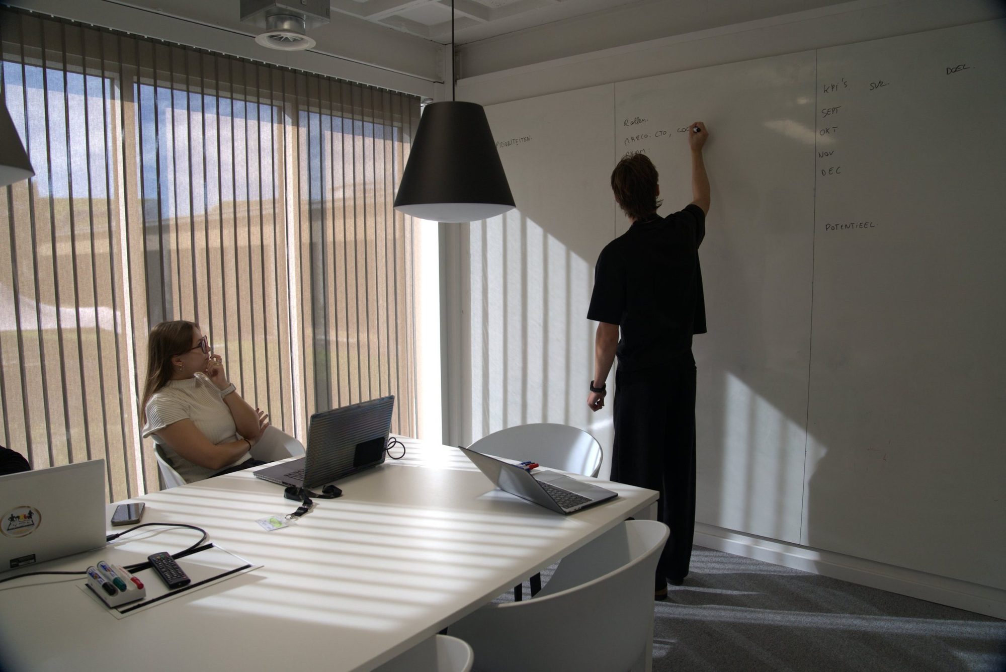 Bram aan het whiteboard terwijl Chiara meekijkt